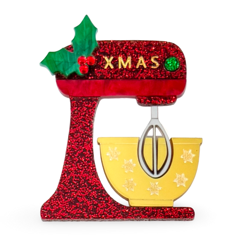 Decorative Christmas brooch shaped like a red glittery mixer with a yellow bowl and 'XMAS' text.